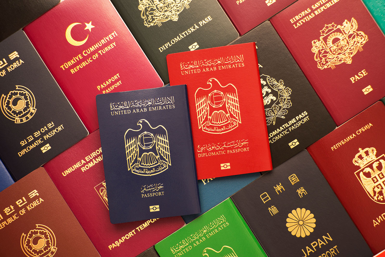 Blue and red biometric passports of United Arab Emirates on background of various documents of many countries of the world